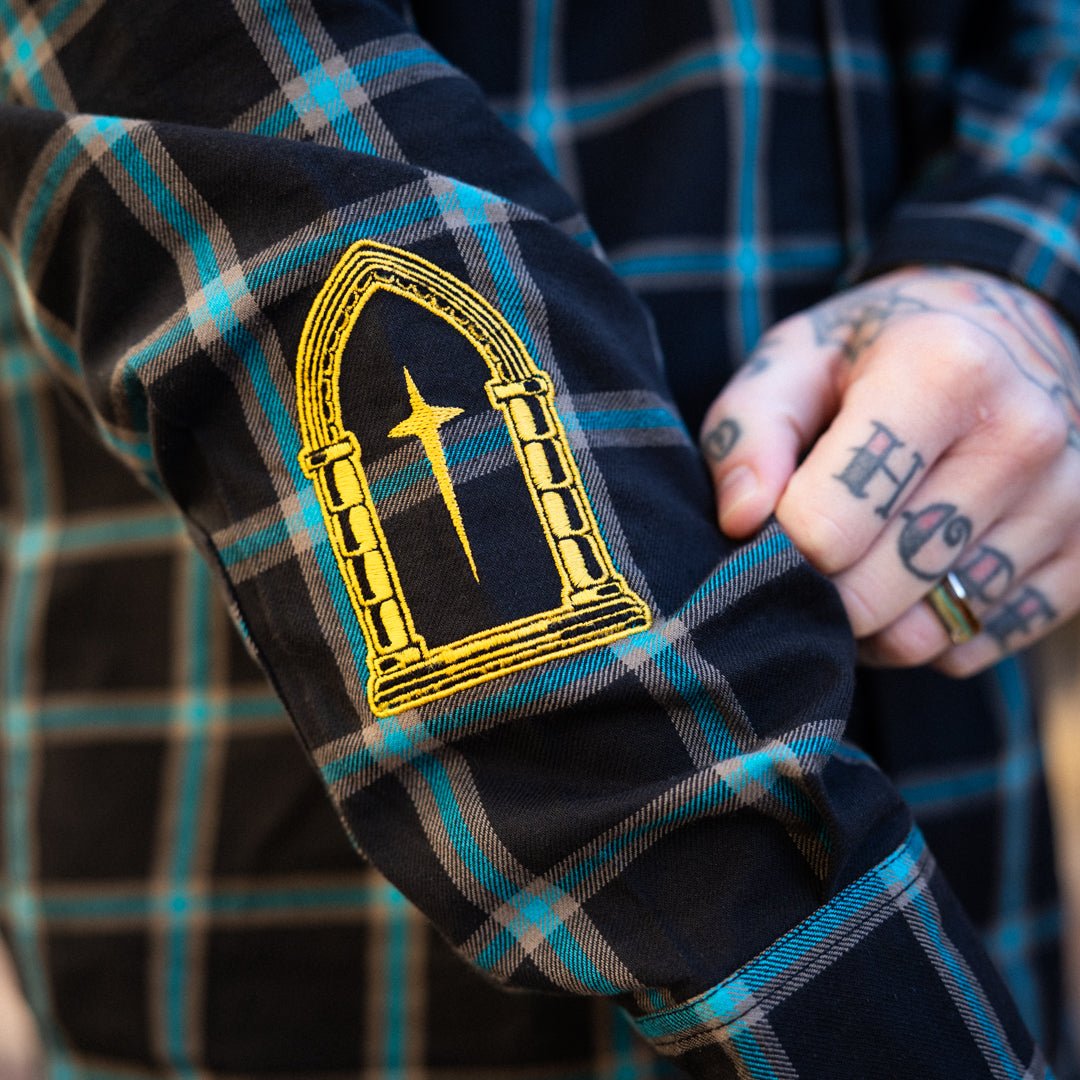 Close-up of a plaid shirt with a gold emblem on a blurred background