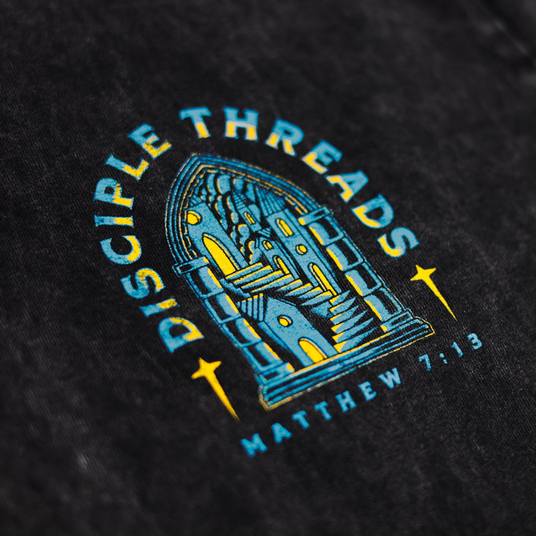 Close-up of a black t-shirt with blue and yellow graphic design and text.