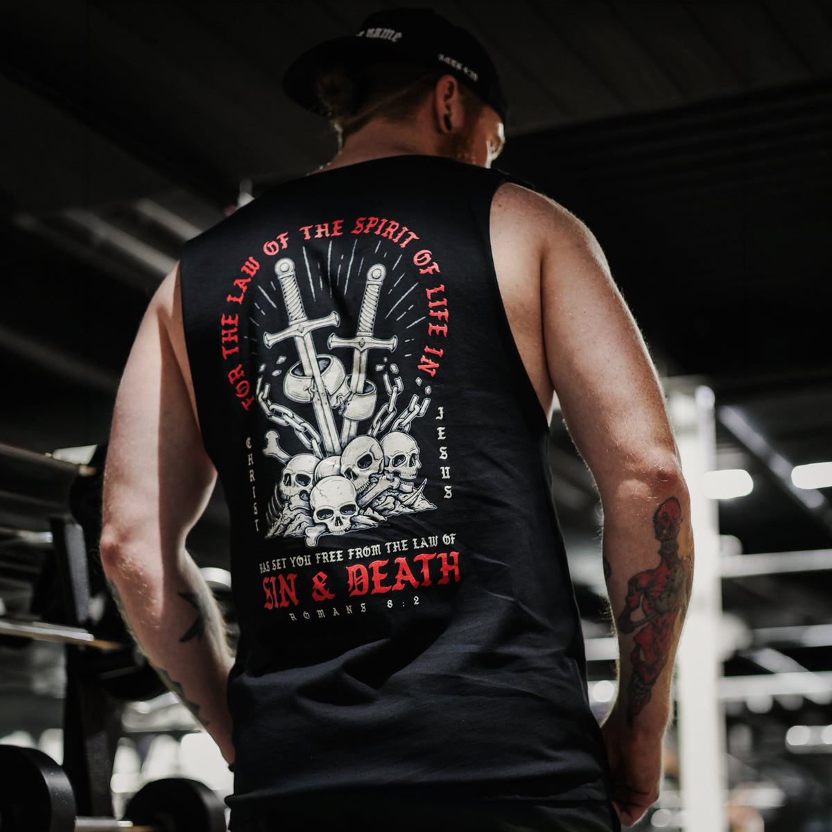 Person wearing a black tank top with a bold Christian graphic design and text.