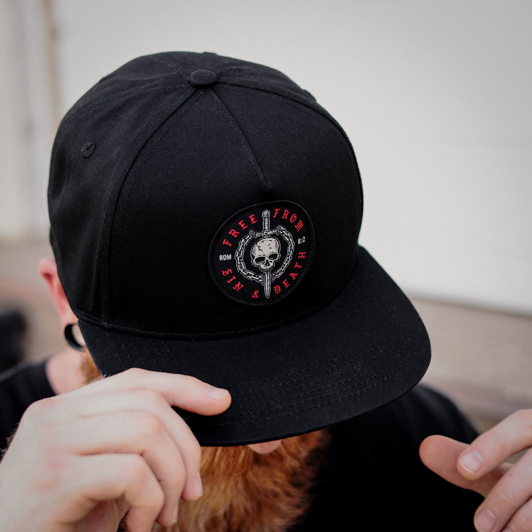 Man wearing Free From Sin and Death Flat Bill Hat based on Romans 5:8.