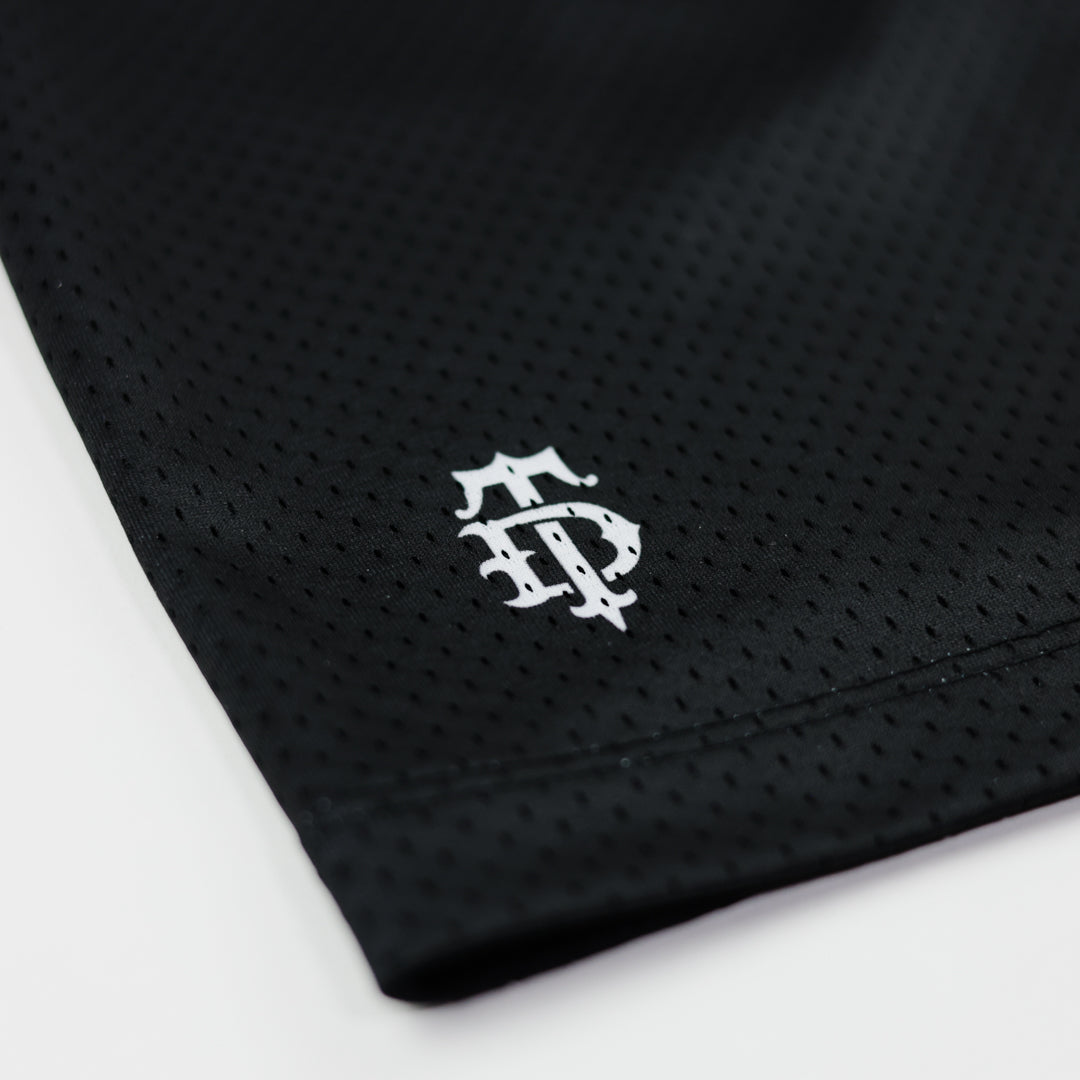 Black athletic shorts with a white logo on a light gray background