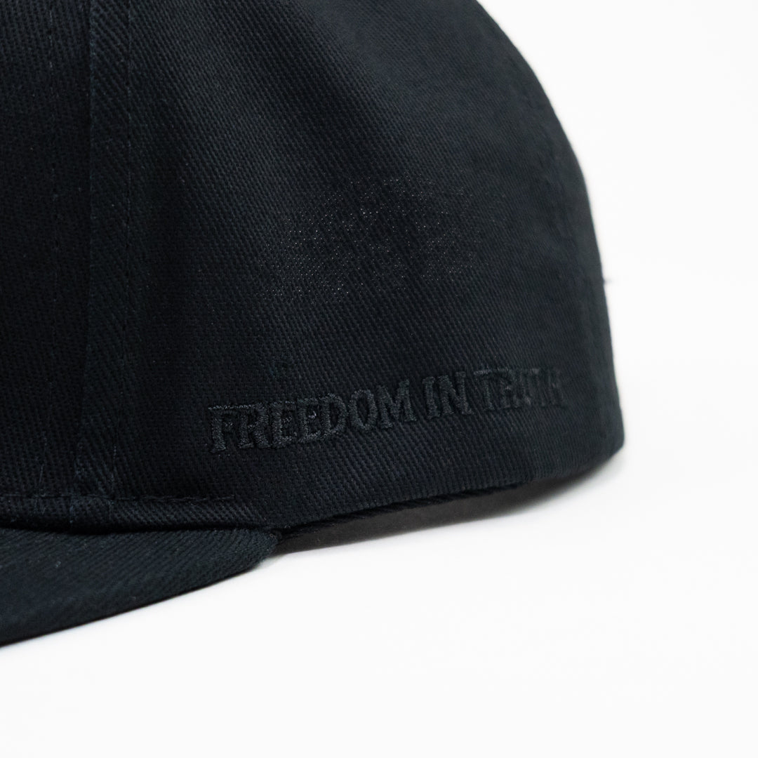 "Freedom in Truth" embroidered on the side of a flat bill cap.