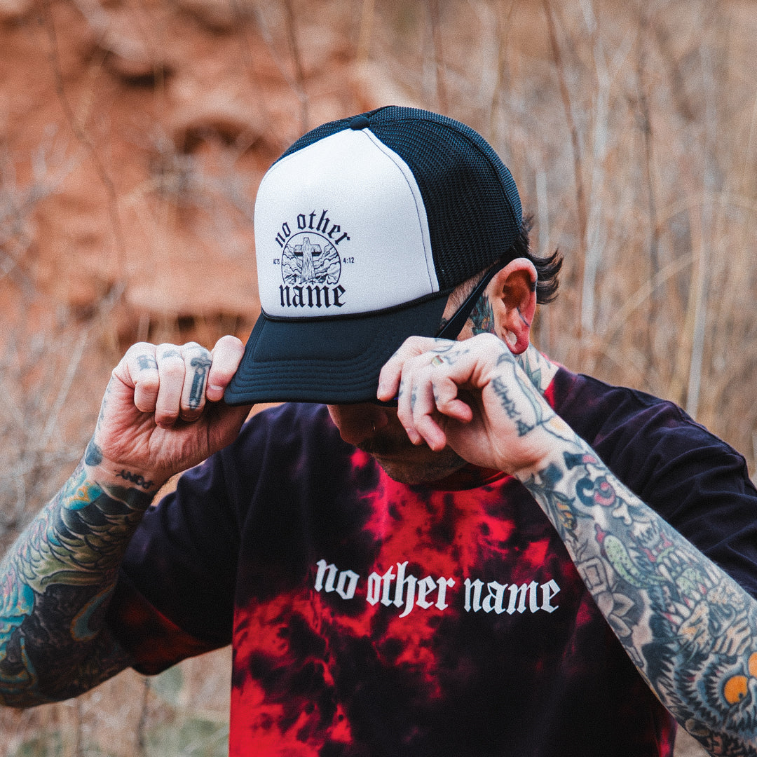 Person wearing a cap and shirt with 'no other name' text in an outdoor setting