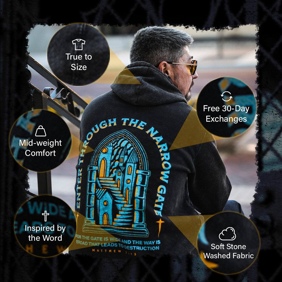 Man wearing a hoodie with text and graphics, sitting outdoors.